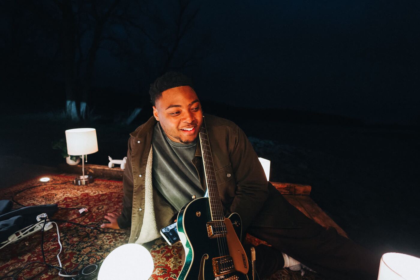 Sincer with a guitar by a lamp