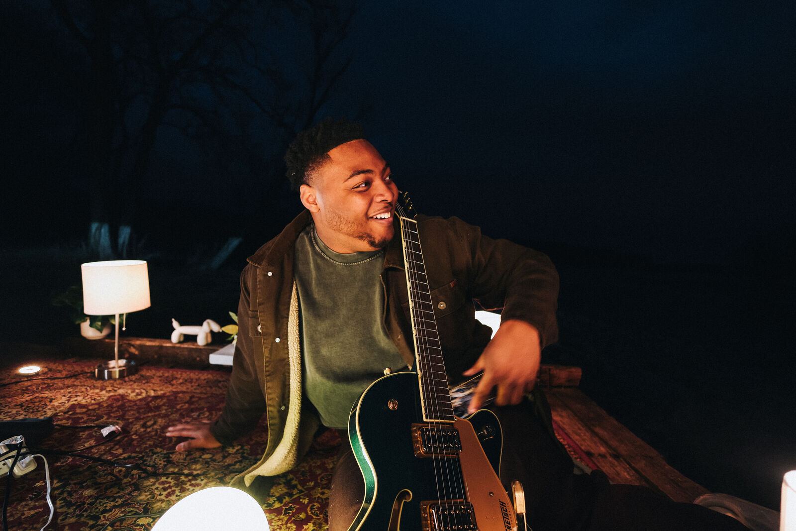 Sincer with a guitar by a lamp